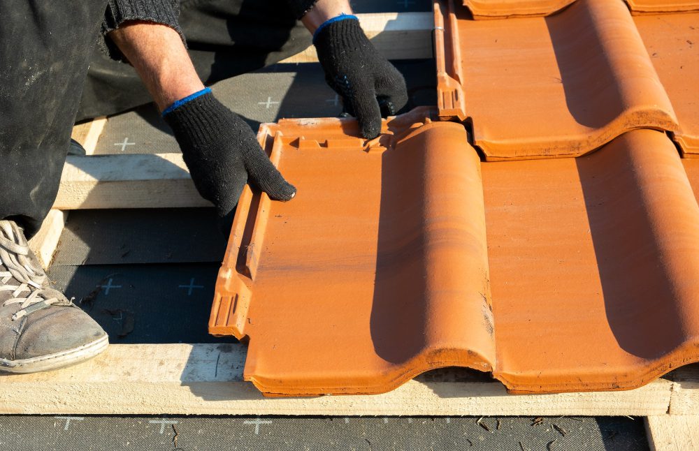 Pose de tuiles sur un toit en construction.