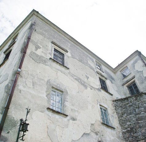 Vieux bâtiment en pierre avec fenêtres grillagées.