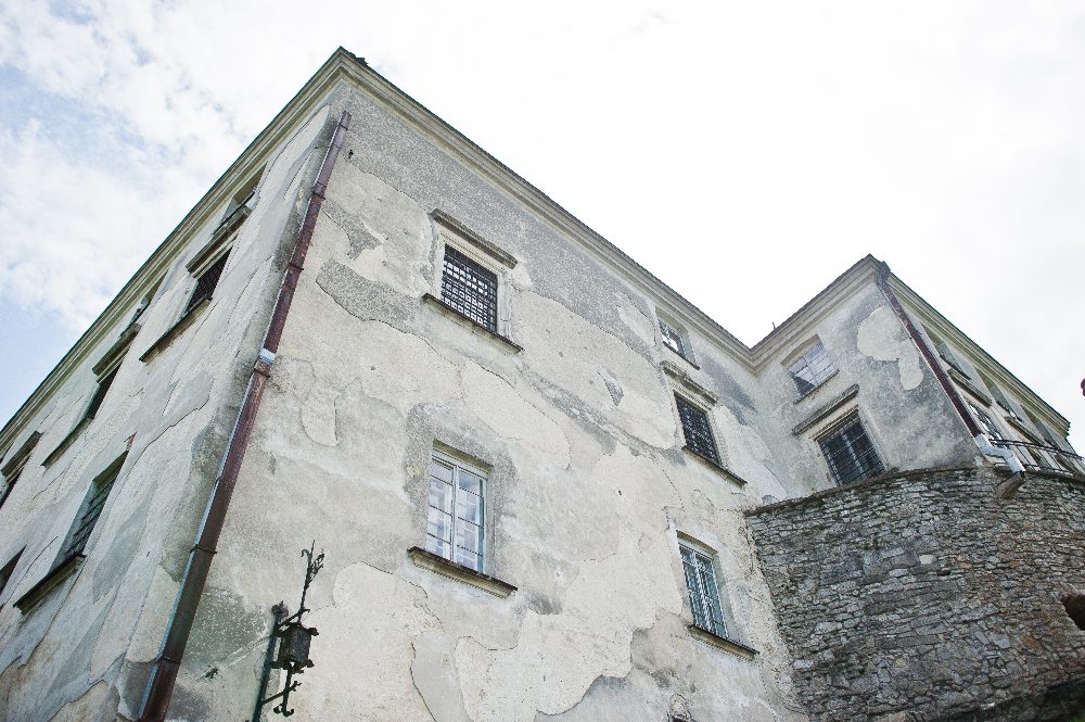 Vieux bâtiment en pierre avec fenêtres grillagées.
