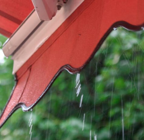 Pluie tombant d'un auvent rouge.
