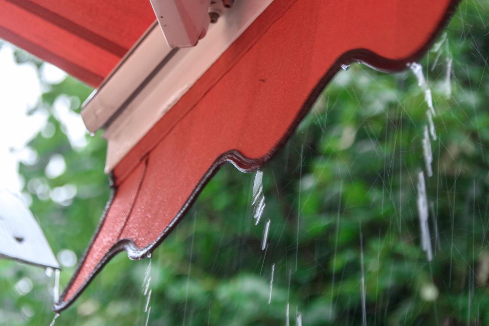 Pluie tombant d'un auvent rouge.