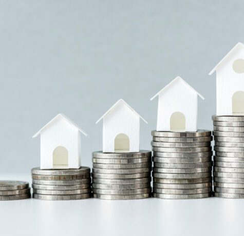 Maisons miniatures sur piles de pièces en croissance.