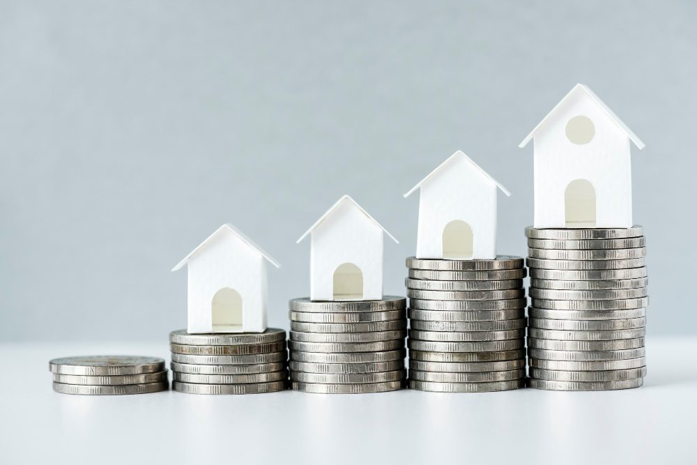 Maisons miniatures sur piles de pièces en croissance.