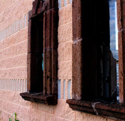 Façade en brique avec fenêtres cassées.
