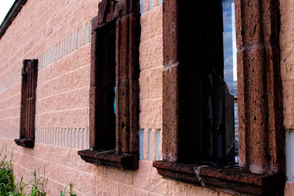 Façade en brique avec fenêtres cassées.