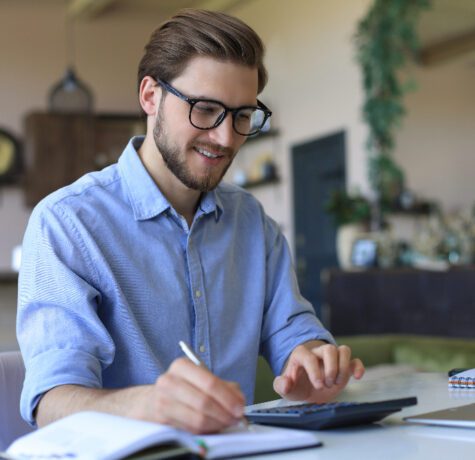 Homme souriant calculant à un bureau moderne.