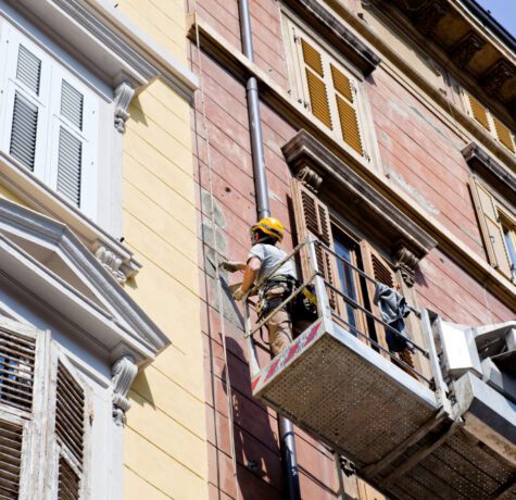 Travailleur rénove façade immeuble sur nacelle élévatrice.