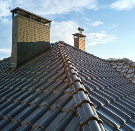 Toiture en tuiles avec cheminées sous ciel bleu.