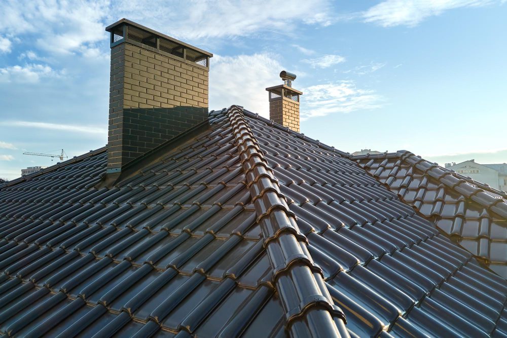 Toiture en tuiles avec cheminées sous ciel bleu.