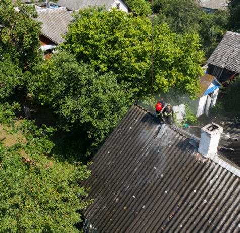 Pompiers arrosant le toit d'une maison en feu.