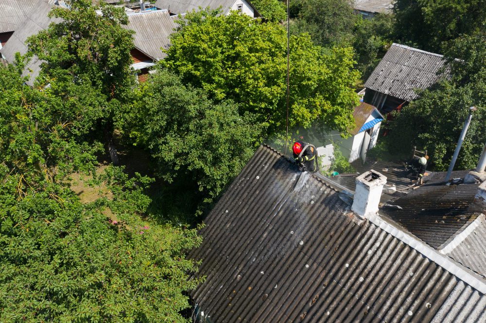 Pompiers arrosant le toit d'une maison en feu.